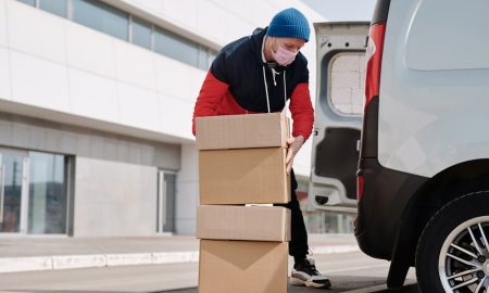 Is dropshipping legal - Delivery man wearing a face mask carrying boxes.